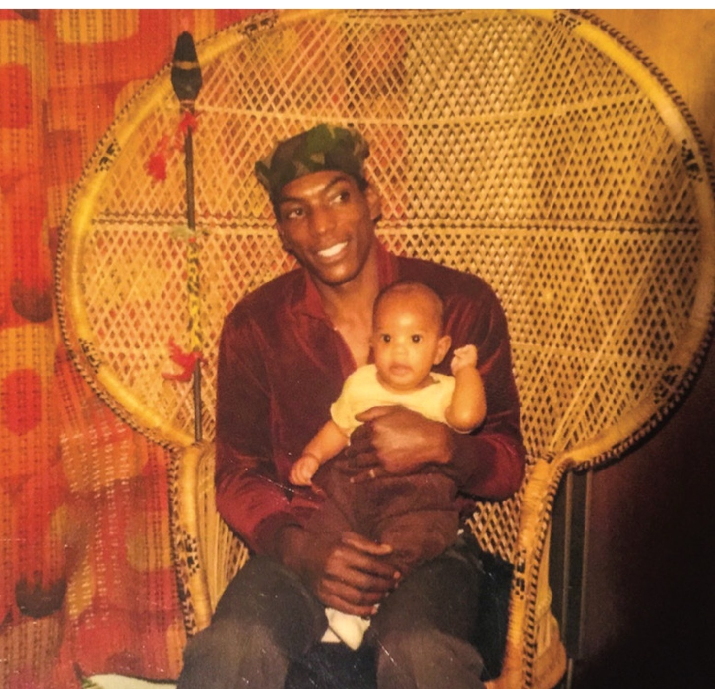 My father holding me in a wicker peacock chair