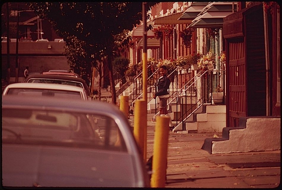 A long row of North Philadelphia rowhouse marble stoops receding down the block, 1973