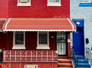 Red brick rowhouse with striped awning and blue trim, 2400 block of Bouvier Street